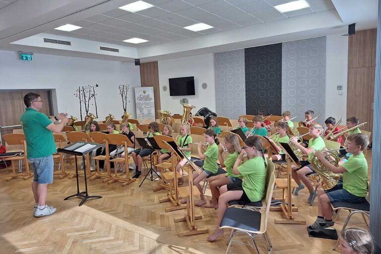 Mehrer junge Personen mit Instrumenten beim Abschlusskonzerts der Bläserklasse und des Jugendorchesters mit Dirigent