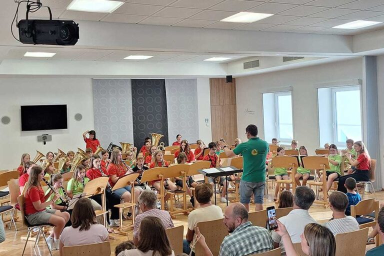 Mehrer junge Personen mit Instrumenten beim Abschlusskonzerts der Bläserklasse und des Jugendorchesters mit Dirigent